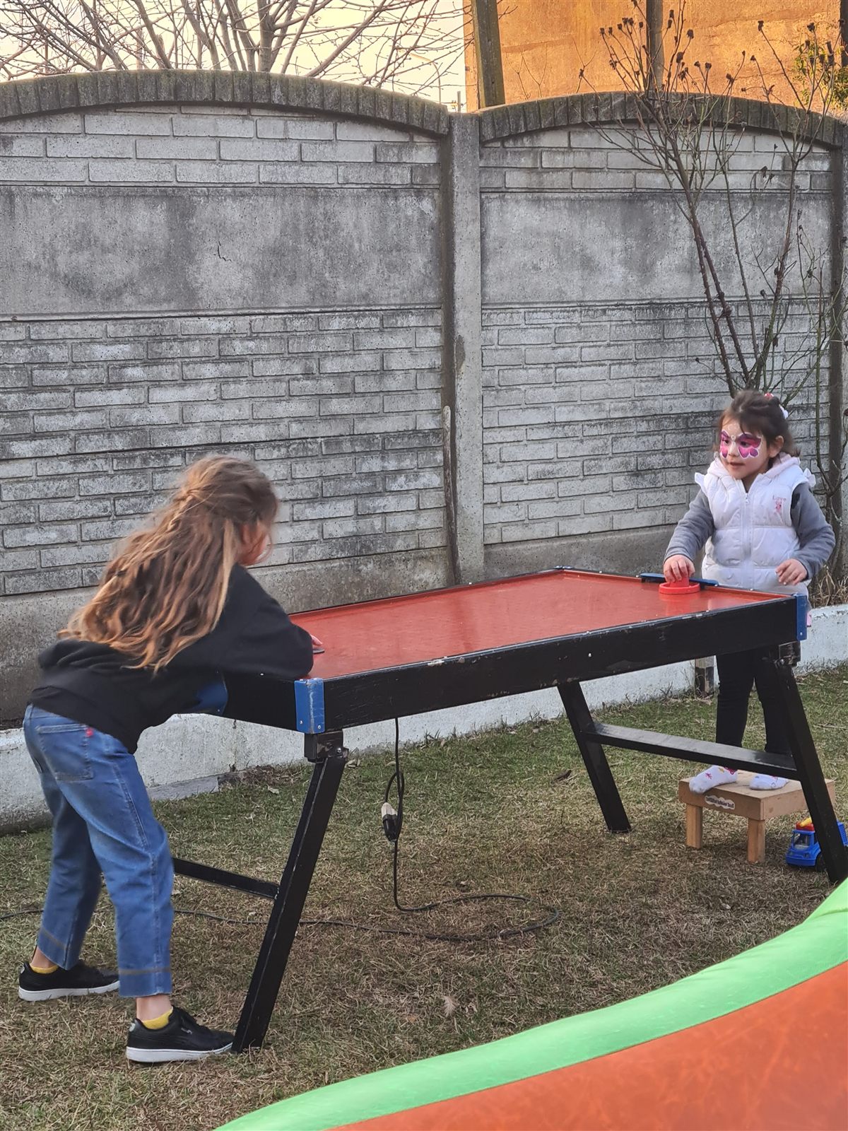 Dos nenas jugando al tejo de mesa en el patio