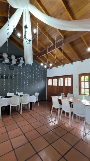 El salón decorado con telas blancas, globos y luces para un cumpleaños de 15
