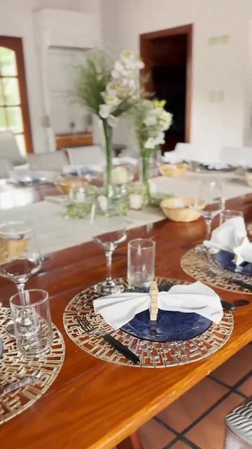 La mesa de madera con la vajilla, las copas y flores